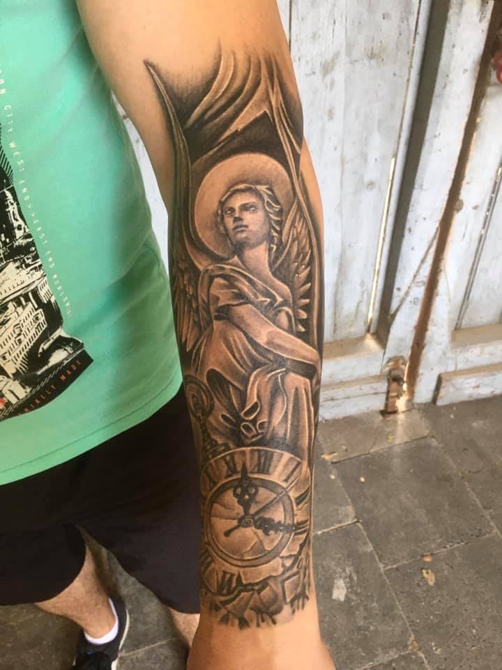 Engelstatue hinter einer Uhr auf dem Unterarm